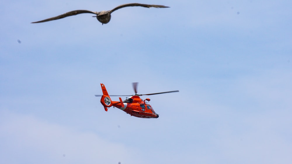 a red helicopter flying through a blue sky