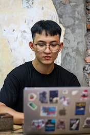 a young man sitting in front of a laptop computer
