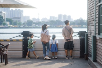 A happy family standing on their newly purchased plot of land with a city skyline in the background.