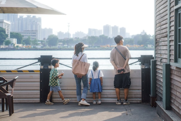 A happy family standing on their newly purchased plot of land with a city skyline in the background.