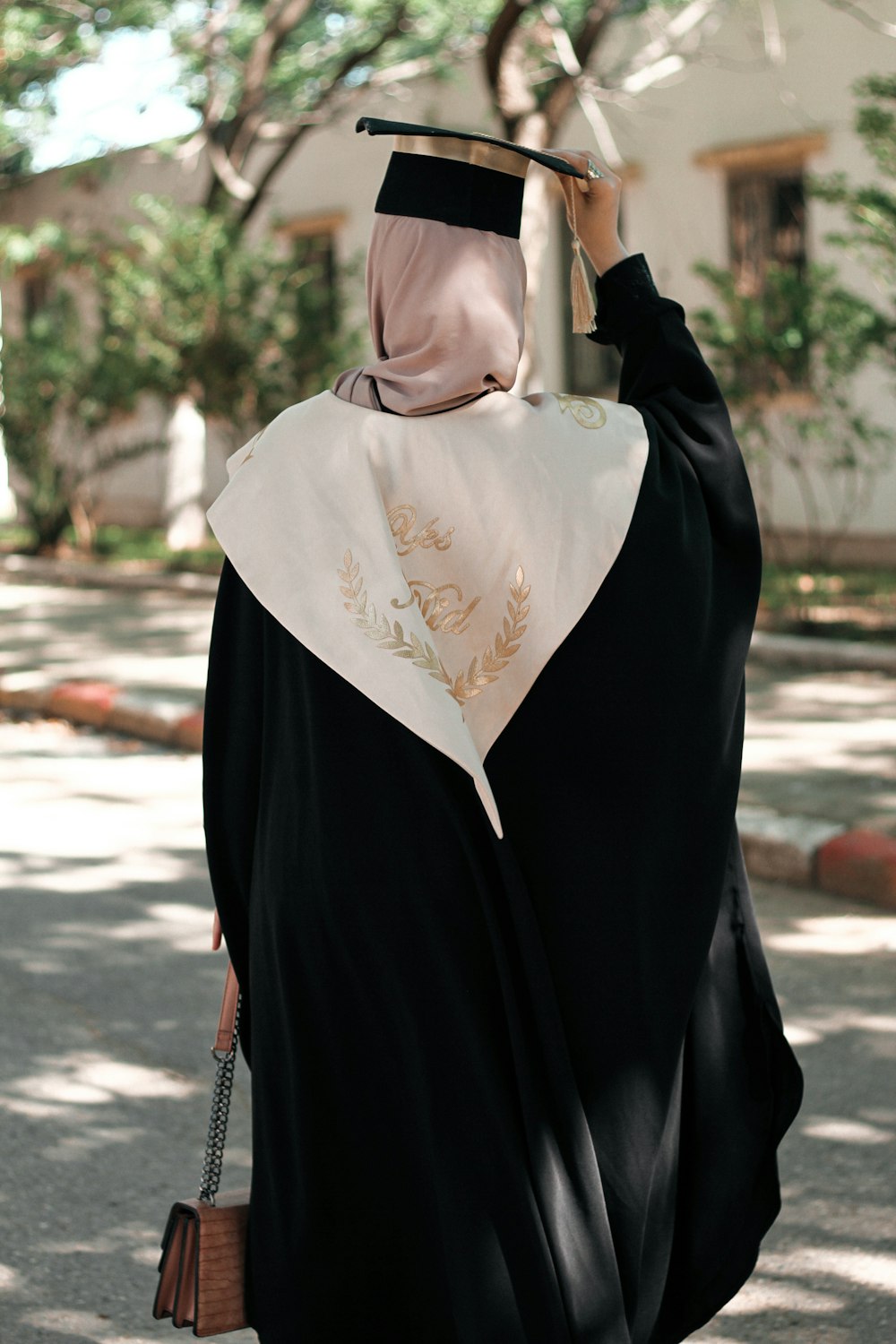 a woman in a graduation gown walking down the street