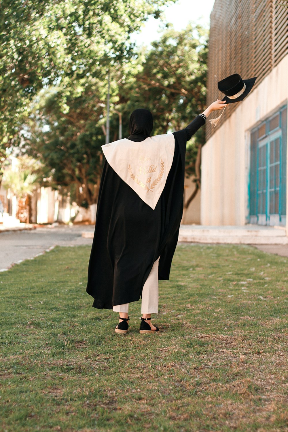 a person in a black and white robe holding a black hat