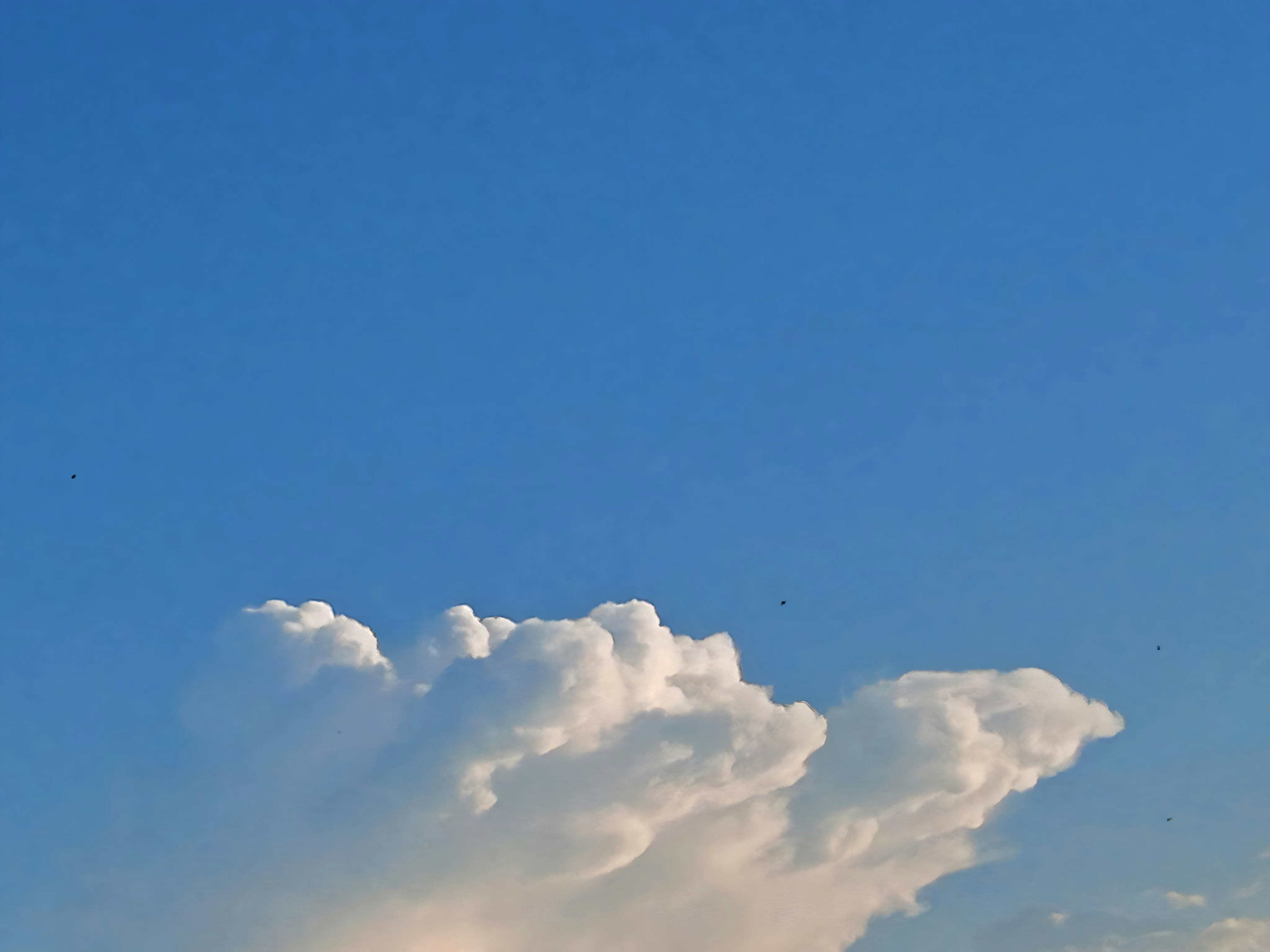a plane flying through a blue sky with clouds