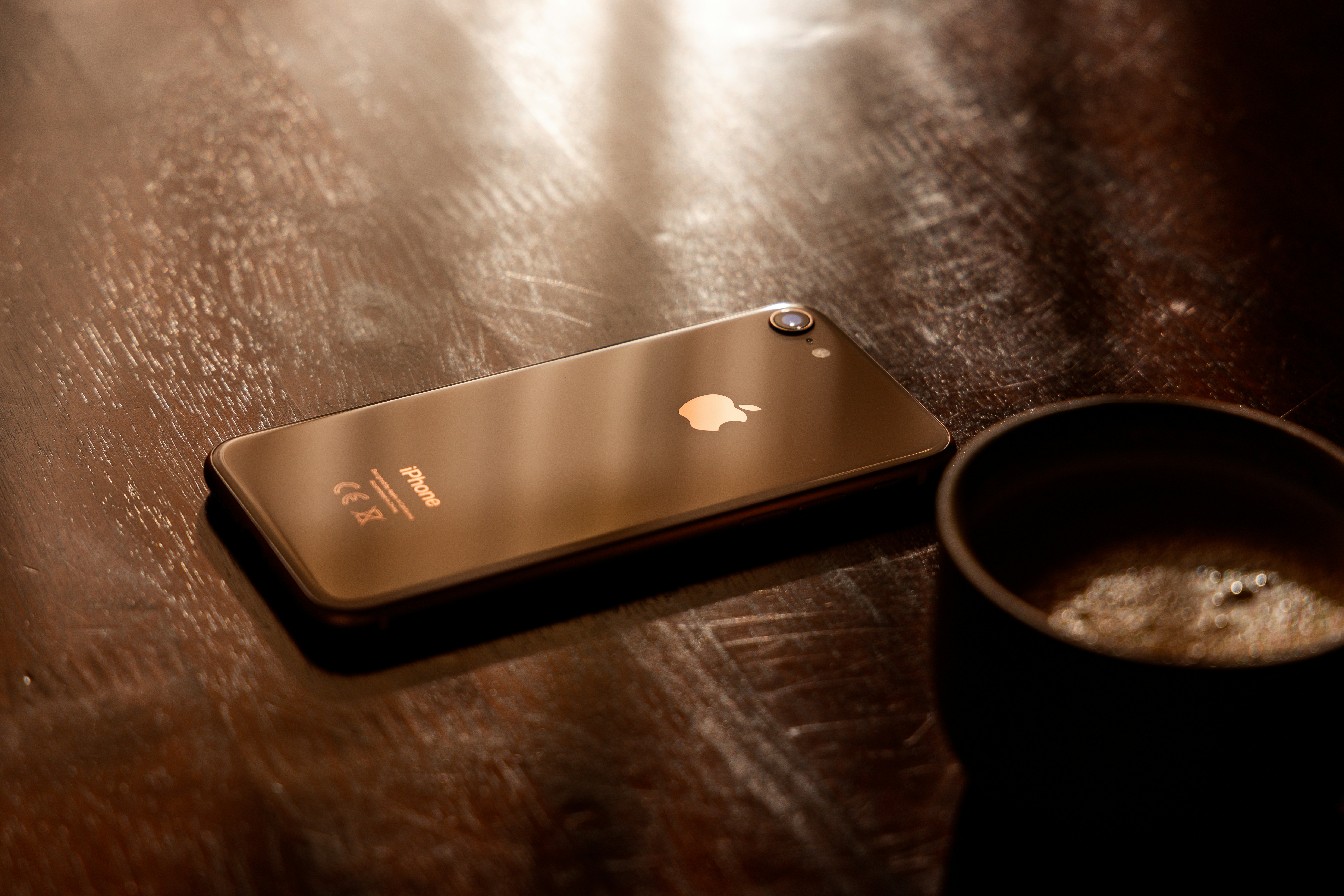 an iphone sitting on a table next to a cup of coffee