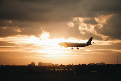 A sleek airplane flying over Dubai's iconic skyline at sunset.