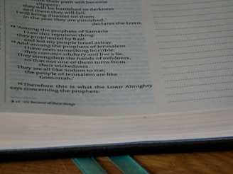 An open book displaying text from a religious scripture with passages discussing prophets and their actions. The text is printed on a page with a slightly yellowed and aged appearance.