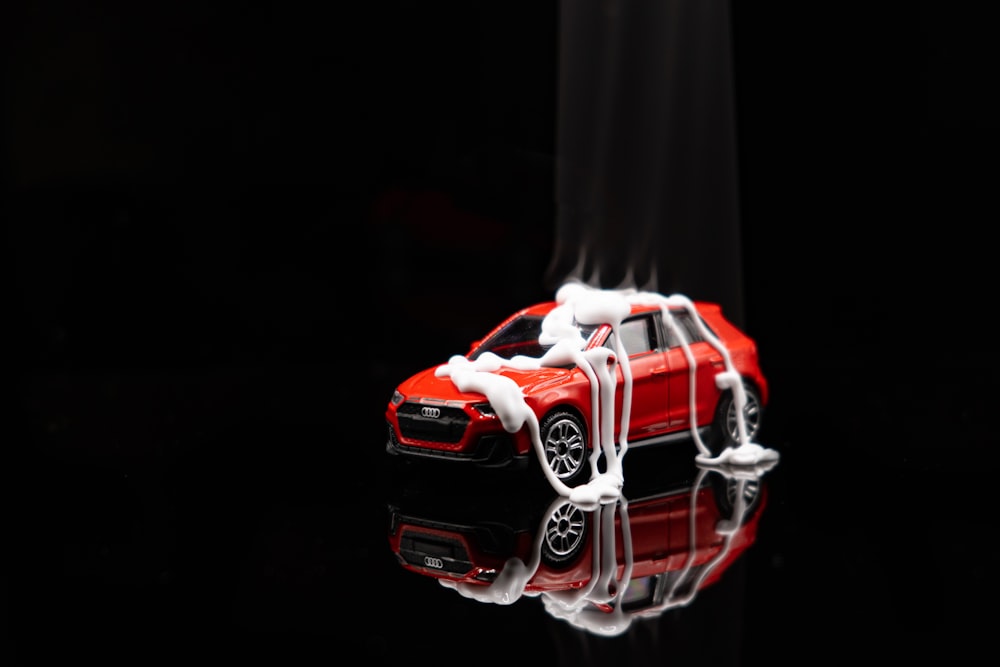 a red toy car on a reflective surface
