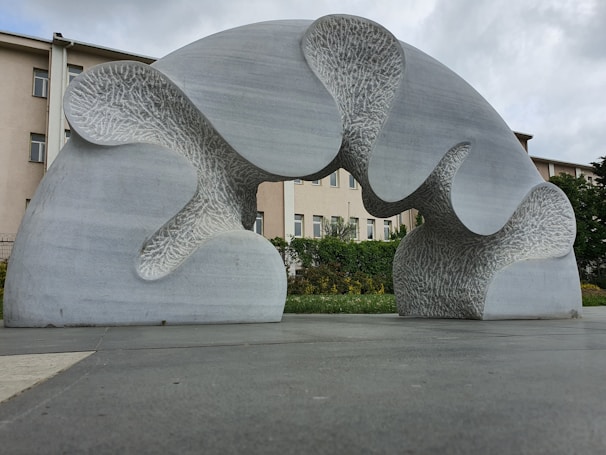 Wide shot of an abstract outdoor sculpture blending metal and stone under natural light.
