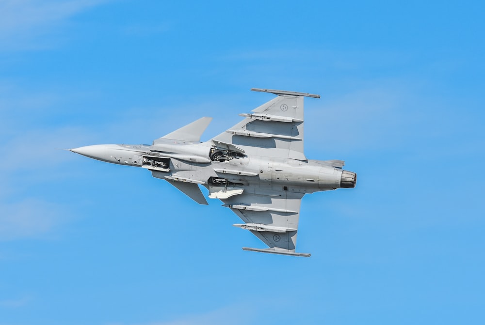 a fighter jet flying through a blue sky