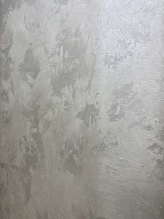 Close-up of a smooth Venetian plaster wall finish in soft gray tones.