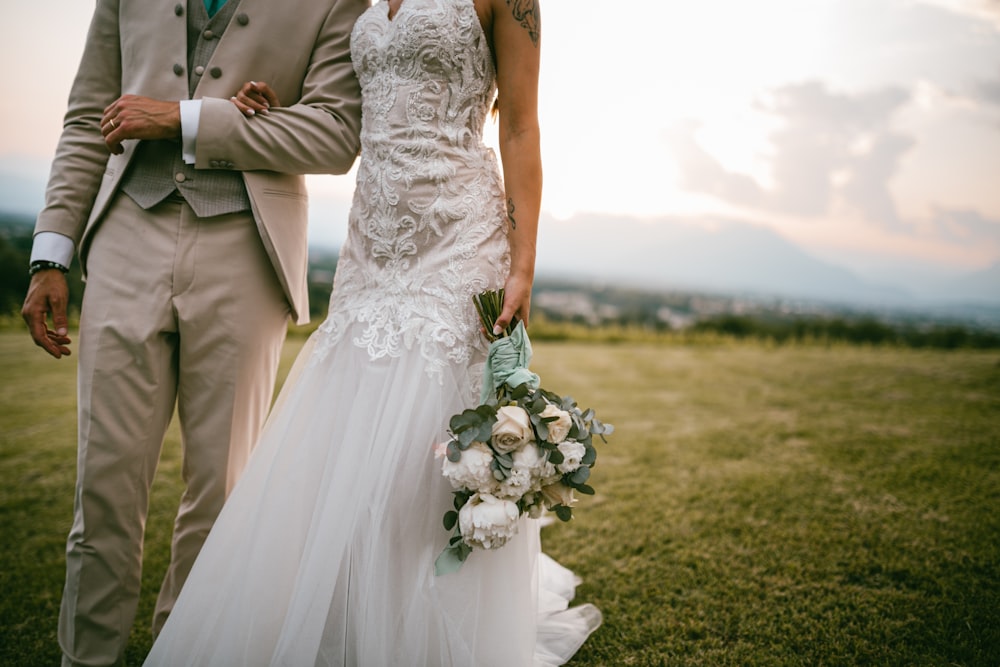 a bride and groom standing in a field