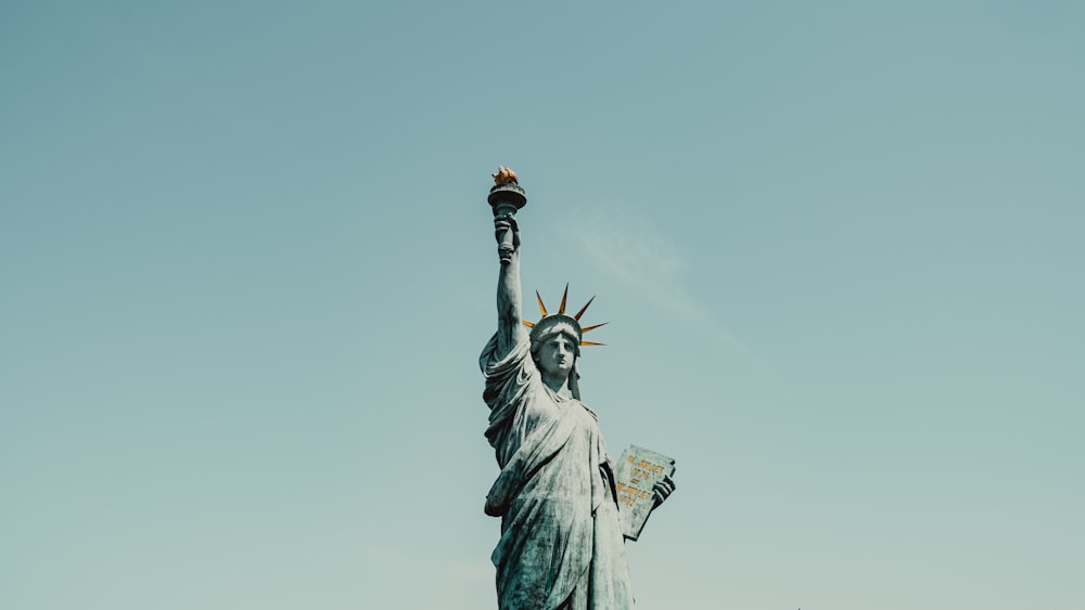 Una estatua de la libertad sosteniendo una bandera en el aire