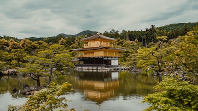 a pagoda in the middle of a lake surrounded by trees