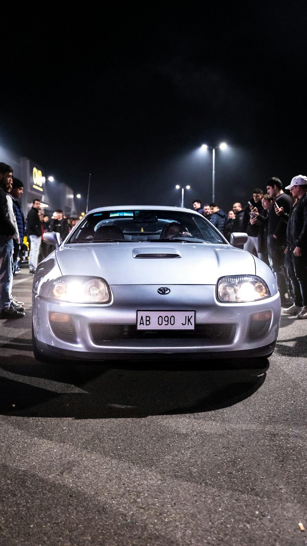 a silver sports car parked in front of a crowd of people