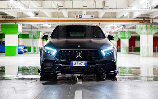 A sleek black car shining under garage lights with blue and gold accents.