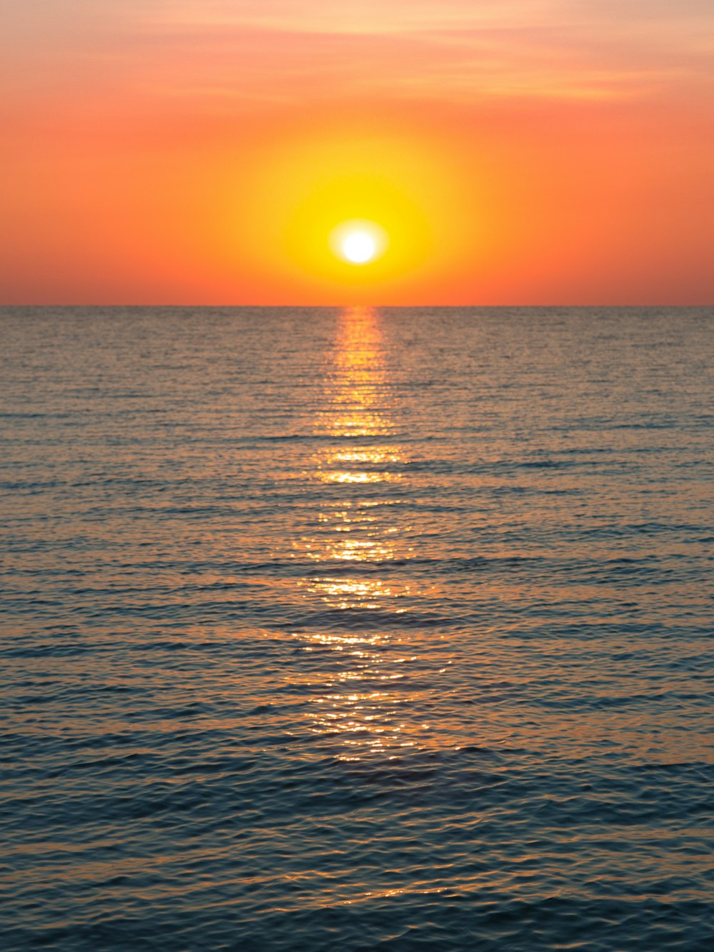 the sun is setting over the ocean with a boat in the water