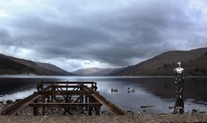 a body of water surrounded by mountains under a cloudy sky