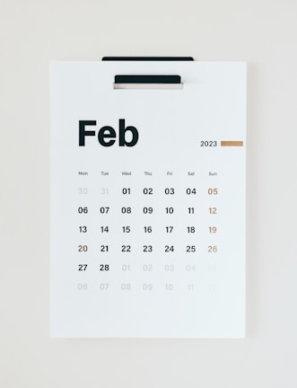 A minimalist wall calendar displays the month of February 2023, with days of the week arranged in a grid. The numbers are printed in black except for the Sundays, which are in brown.