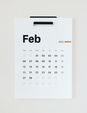 A minimalist wall calendar displays the month of February 2023, with days of the week arranged in a grid. The numbers are printed in black except for the Sundays, which are in brown.