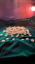 Golden coins spilling from an ornate chalice under soft purple lighting.