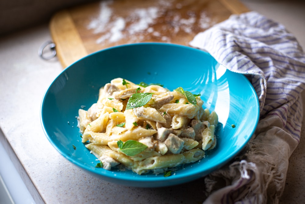 a blue bowl filled with pasta on top of a counter