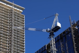 A sturdy scaffolding structure set up at a bustling construction site under a clear blue sky in the Middle East.