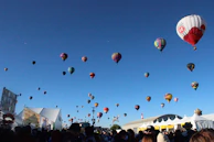 An overhead capture of a colorful hot air balloon festival with dozens of balloons in the sky.