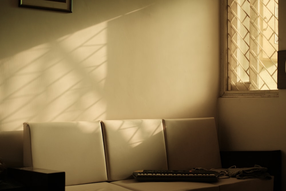 a couch with a remote control on it in front of a window