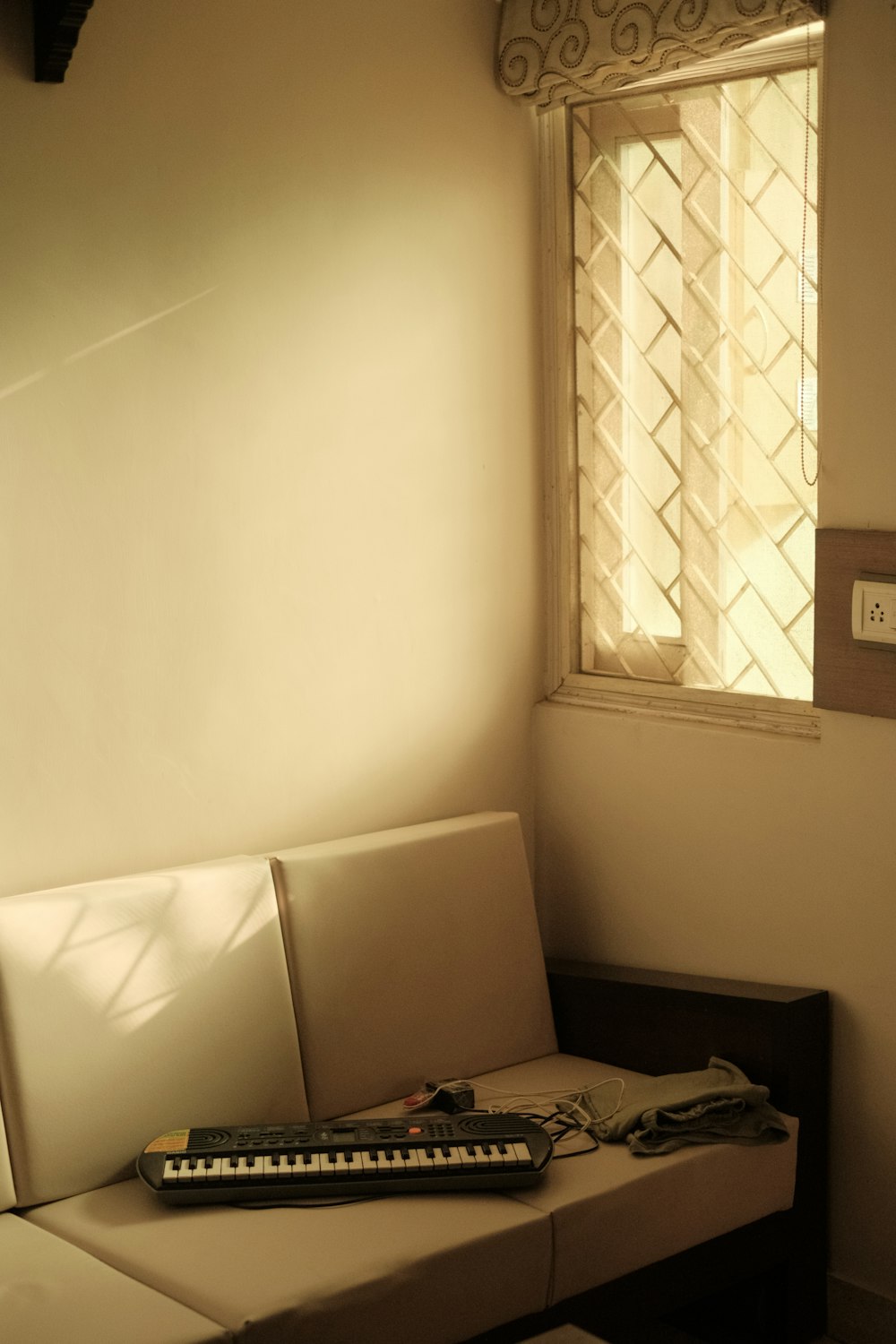 a couch with a keyboard on it in front of a window