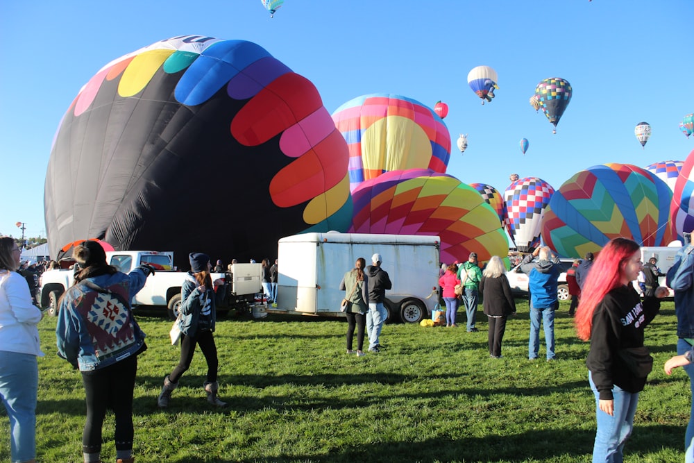 a group of people standing around hot air balloons