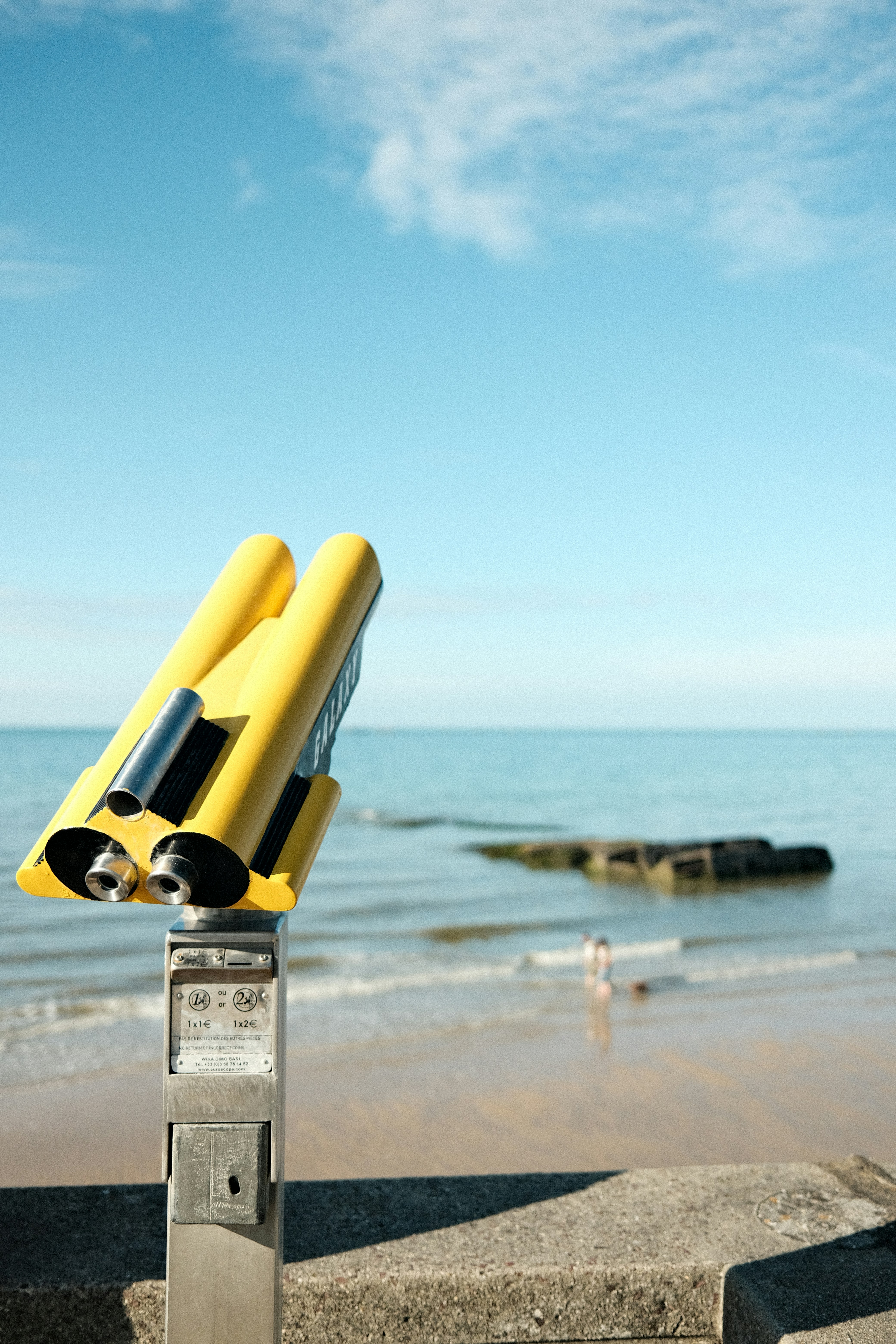 a parking meter sitting on top of a beach next to the ocean