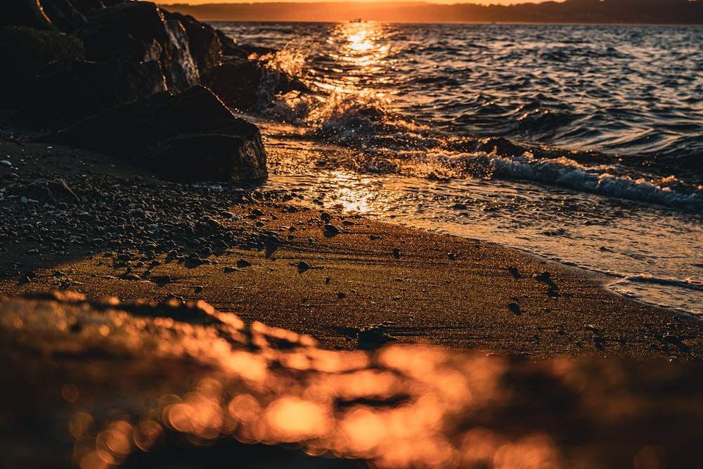 the sun is setting over the water at the beach