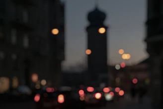 A blurred city skyline at dusk with lights starting to turn on.