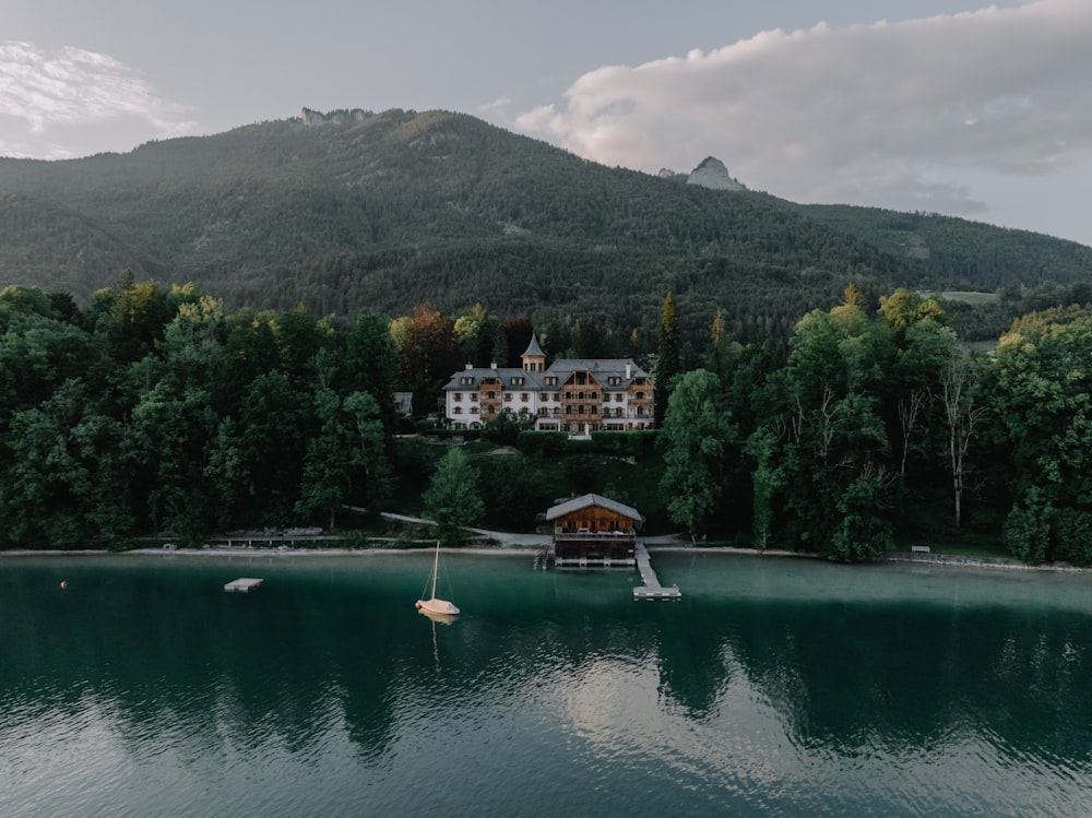 a boat floating on top of a lake next to a lush green hillside