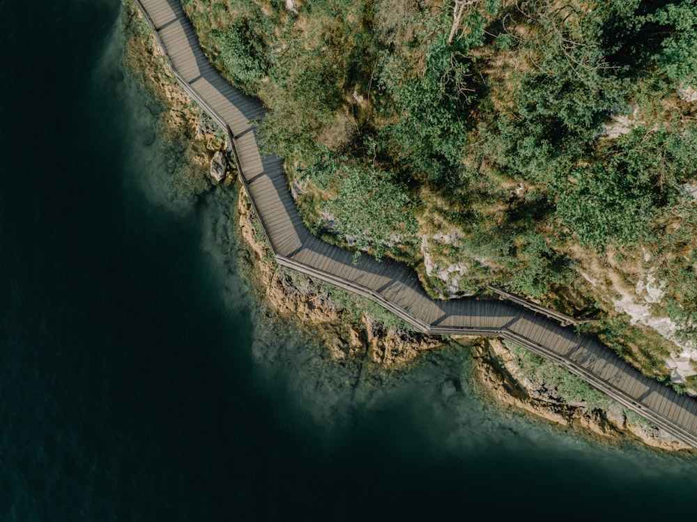 an aerial view of a winding road next to a body of water