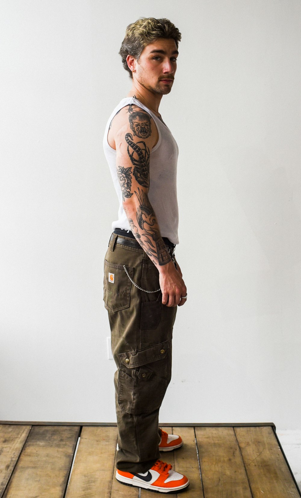 a man with tattoos standing on a wooden floor
