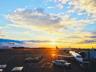 Airplanes taking off from an airport runway during sunset.
