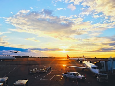 Airplanes taking off from an airport runway during sunset.
