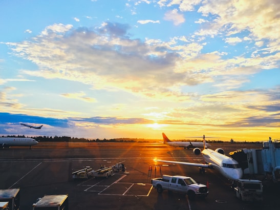 Bird's-eye view of a busy airport runway with planes taking off during sunset