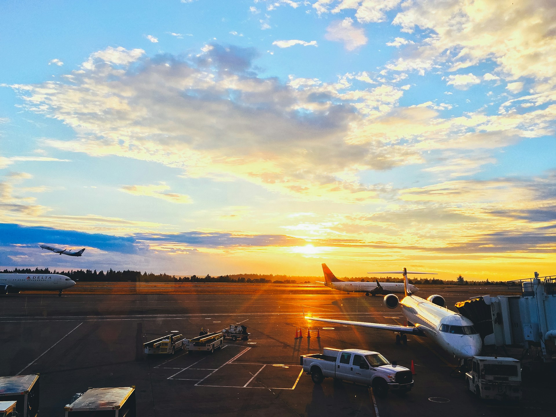 A vibrant aerial shot of a bustling airport runway at sunset, planes lined up ready for takeoff.