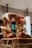 A basket filled with artisan bread, featuring a large, uniquely shaped loaf with an abstract design placed prominently. The background includes softly blurred interior lights and shelves with various items, creating a cozy atmosphere.