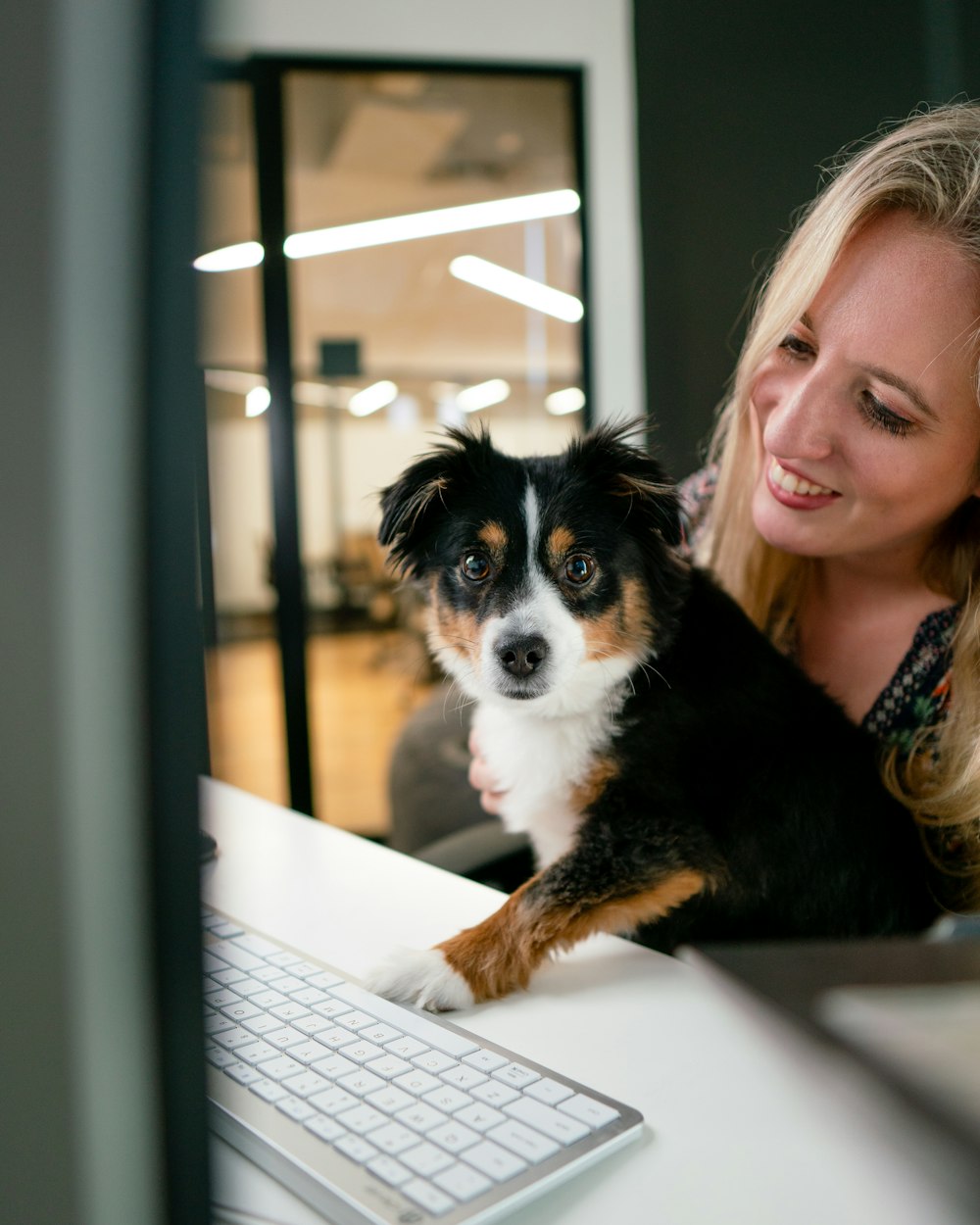 a woman sitting at a desk with a dog on her lap