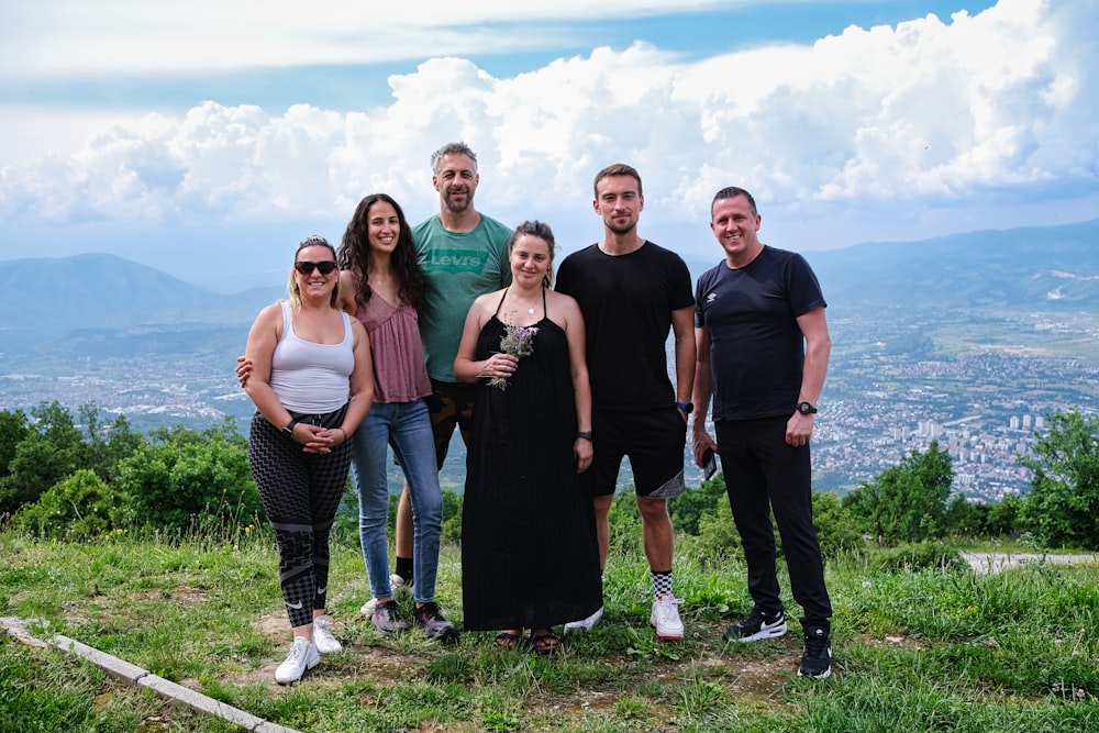 a group of people standing on top of a lush green hillside