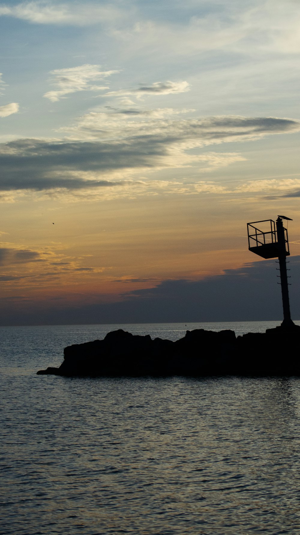 a light tower sitting on top of a rock in the ocean