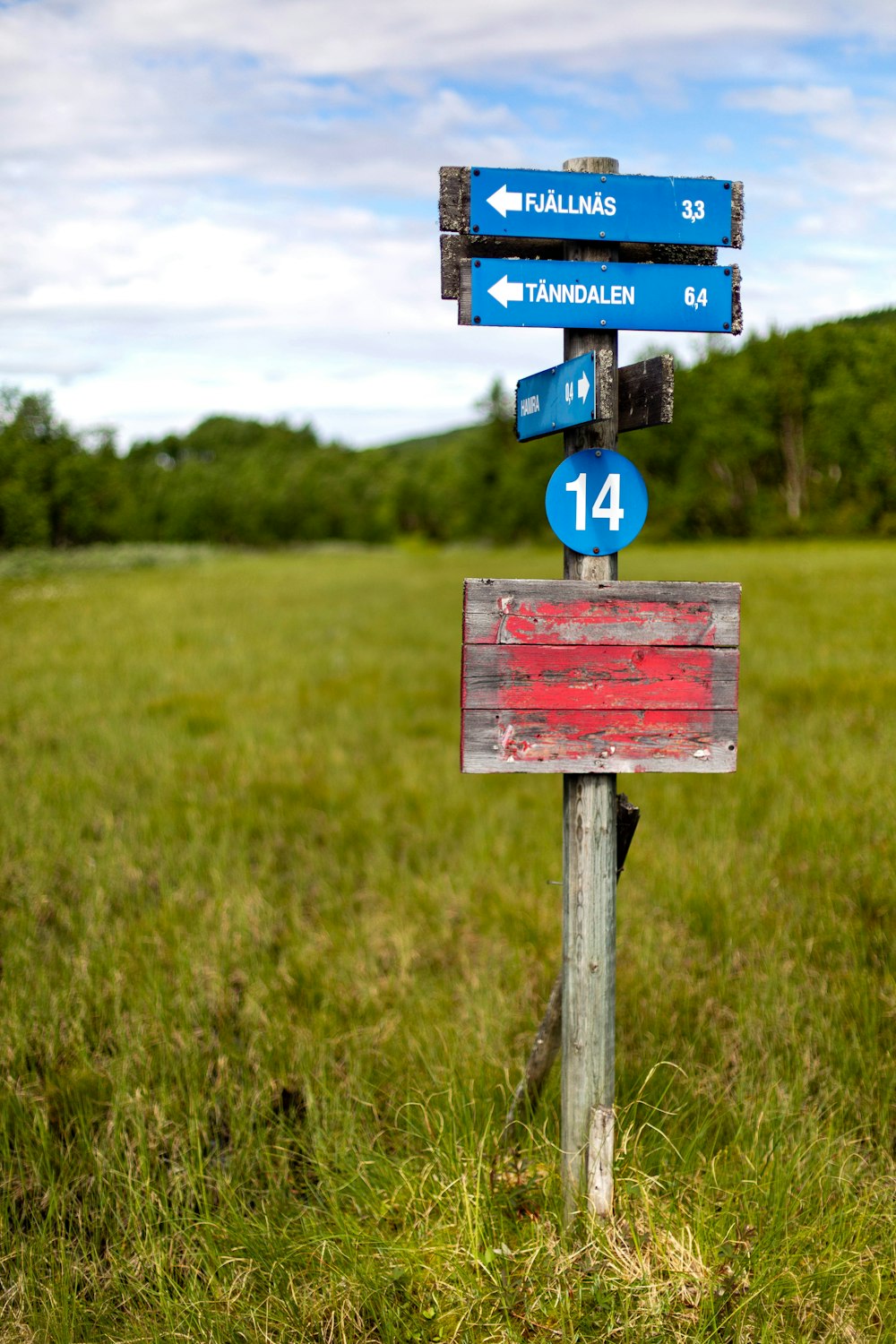 a wooden sign in the middle of a grassy field