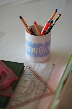 a cup filled with pencils sitting on top of a table