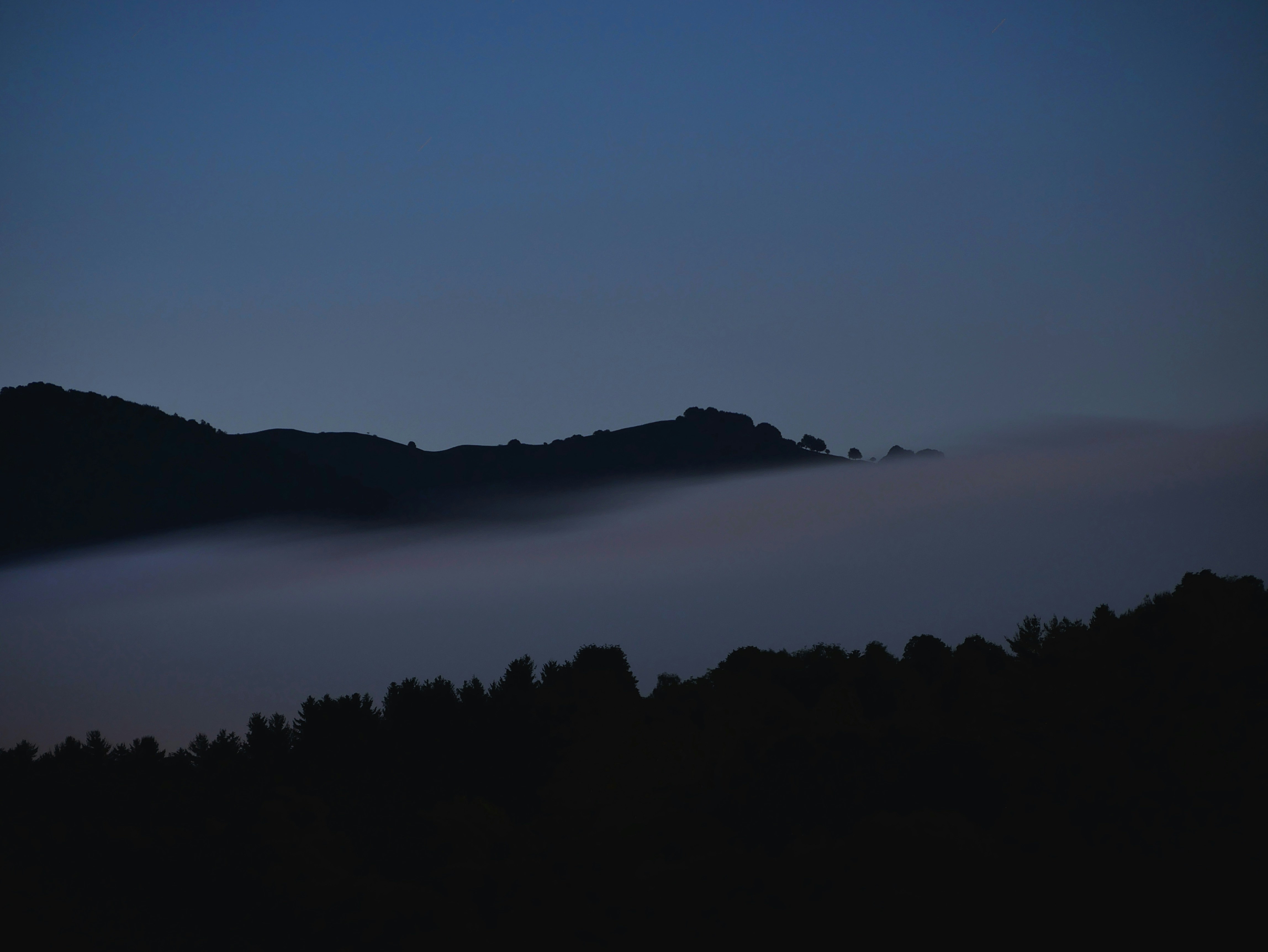 Ein Hügel, der nachts mit einem Himmelshintergrund in Nebel gehüllt ist