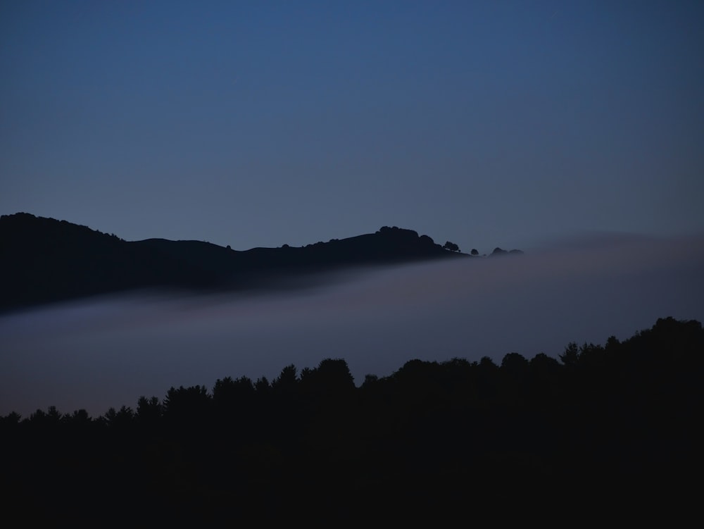 a hill covered in fog at night with a sky background
