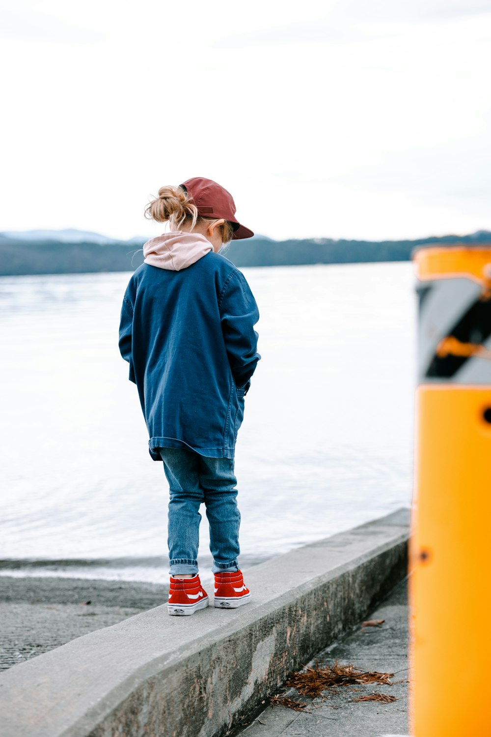 a person standing on a concrete ledge next to a body of water