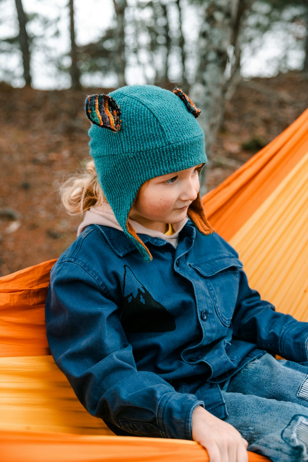 a little girl sitting in a hammock in the woods